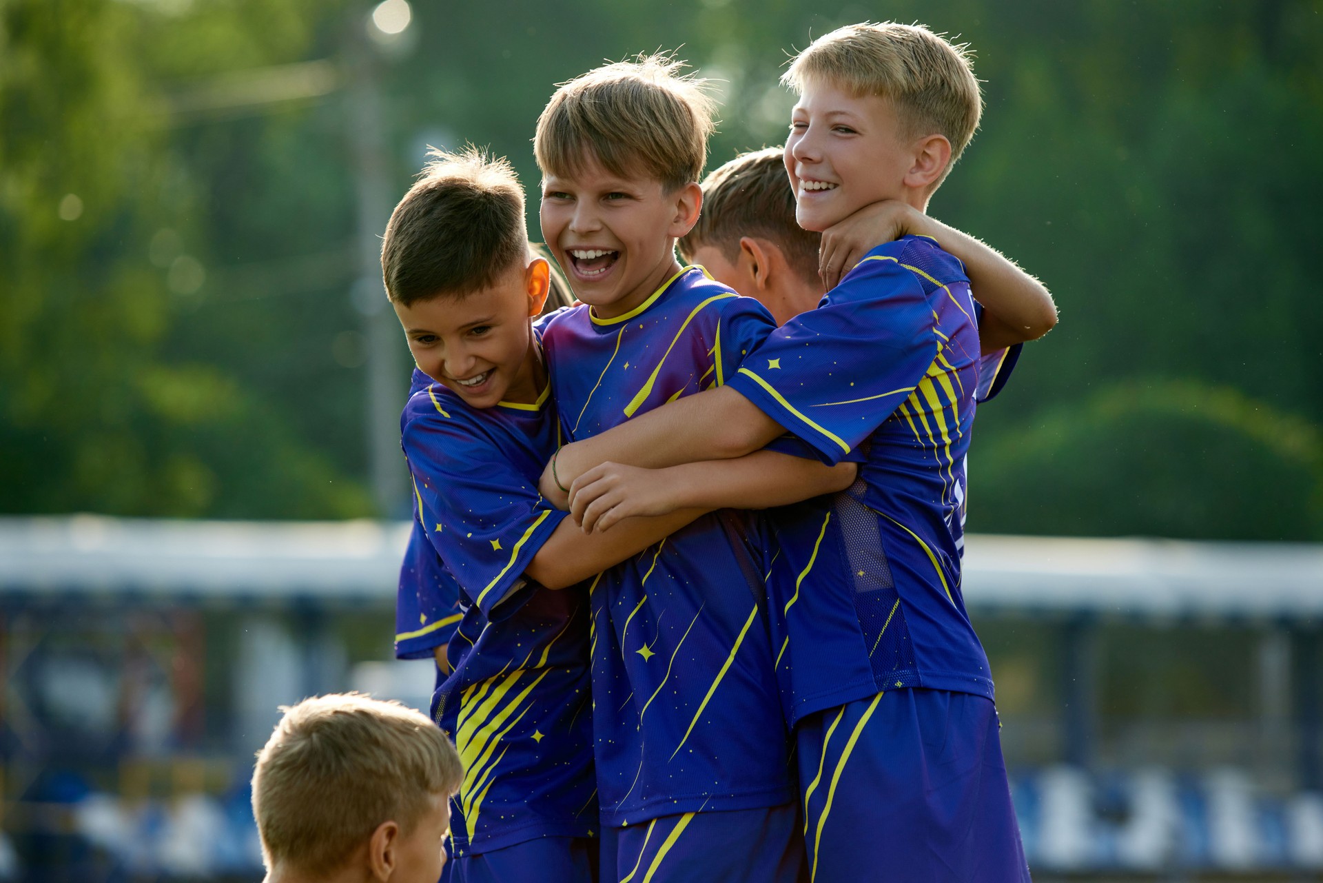 Dynamic moment of victory. Boys, friends in blue uniform, soccer players in motion, jumping and hugging, celebrating winning game.