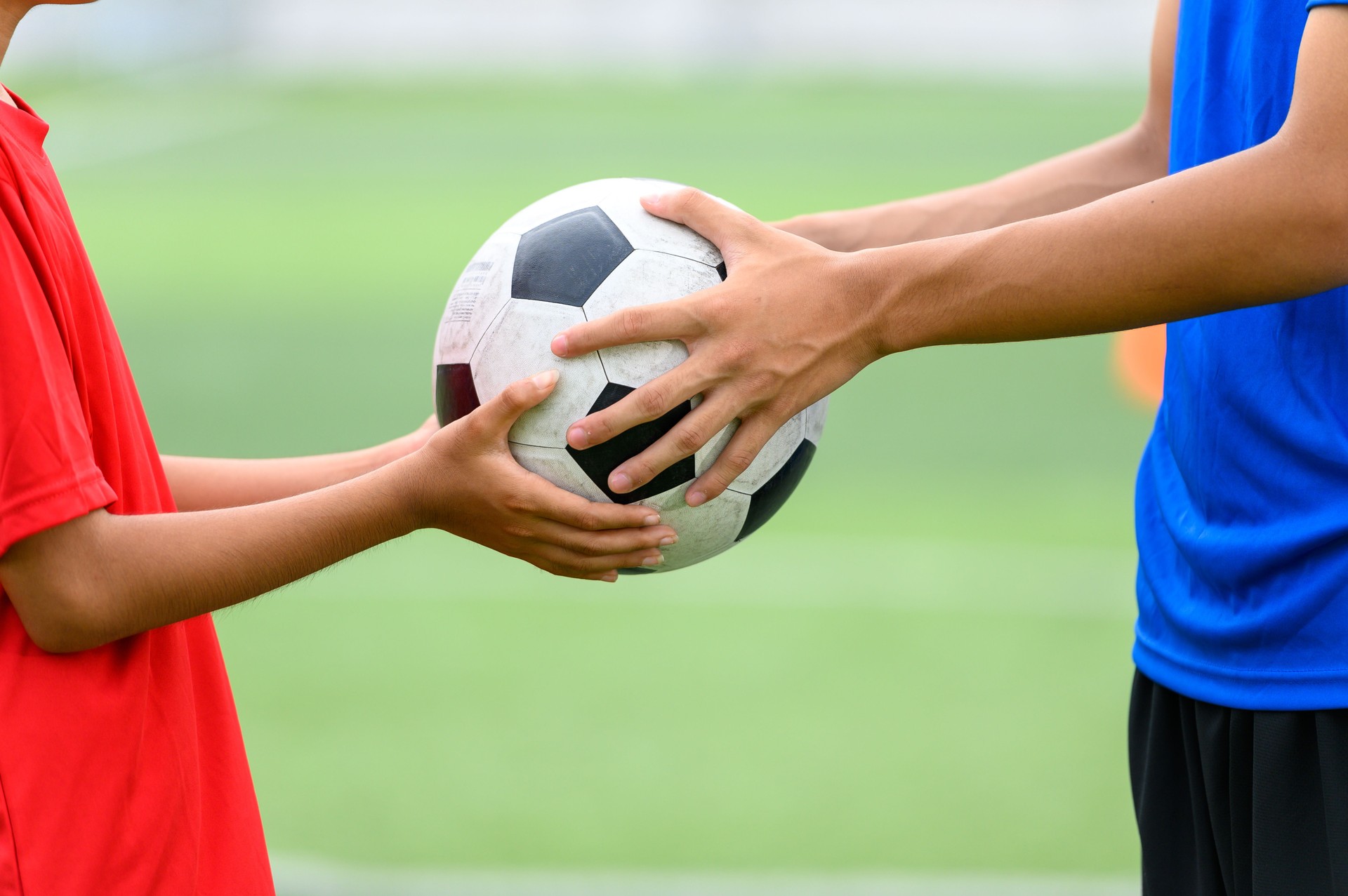 Asian teenager Football Players fair play handed a soccer ball to his brother